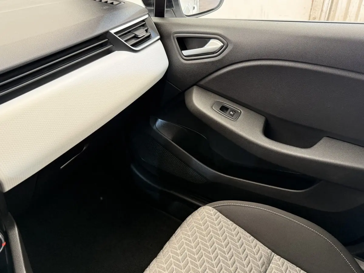 Vue intérieure côté passager avant de la Renault Clio Evolution TCe 100 GPL 2023 avec tableau de bord blanc et porte noire.