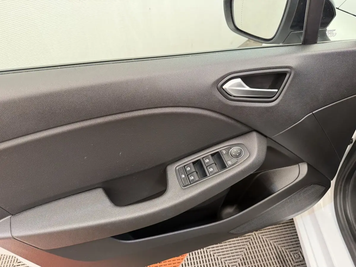 Vue intérieure sur la porte avant gauche de la Renault Clio blanche, avec commandes électriques des vitres et rétroviseurs.