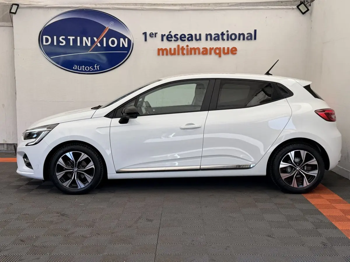 Profil côté gauche d'une Renault Clio Evolution TCe 100 GPL blanche, avec jantes alliage et rétroviseurs noirs.