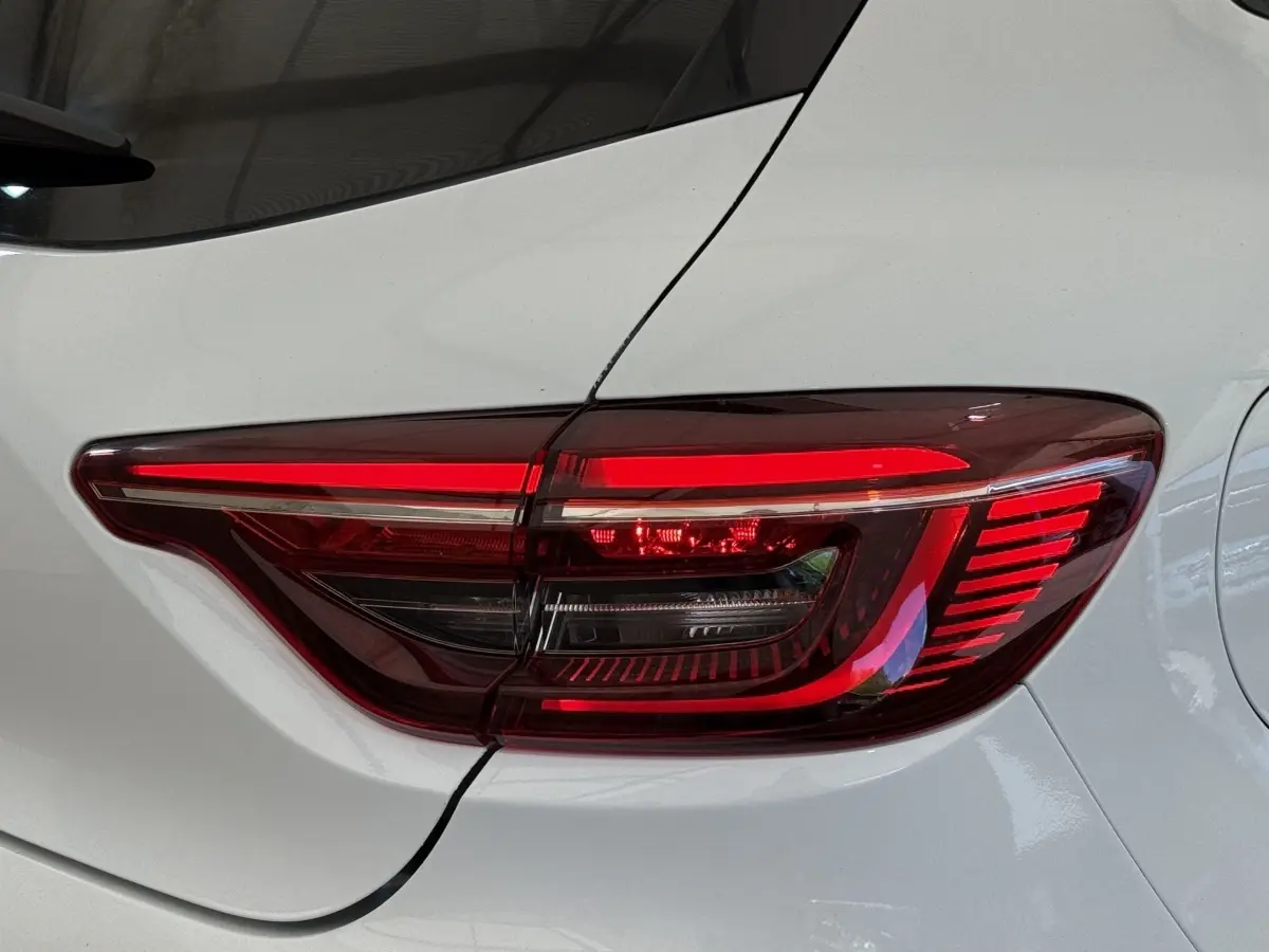 Feu arrière droit allumé sur Renault Clio blanc Evolution TCe 100 GPL, vue rapprochée du coffre et de la porte arrière.
