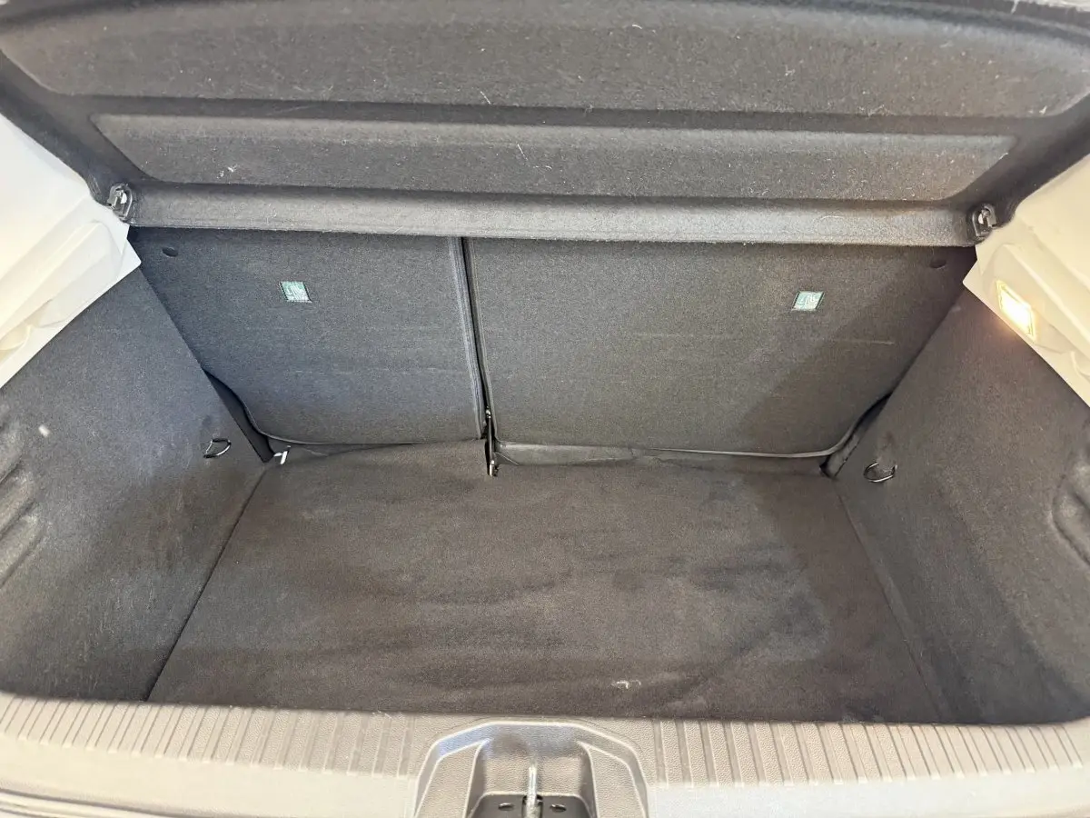 Vue intérieure du coffre noir de la Renault Clio Evolution TCe 100 GPL blanc, montrant l'espace de chargement vide.