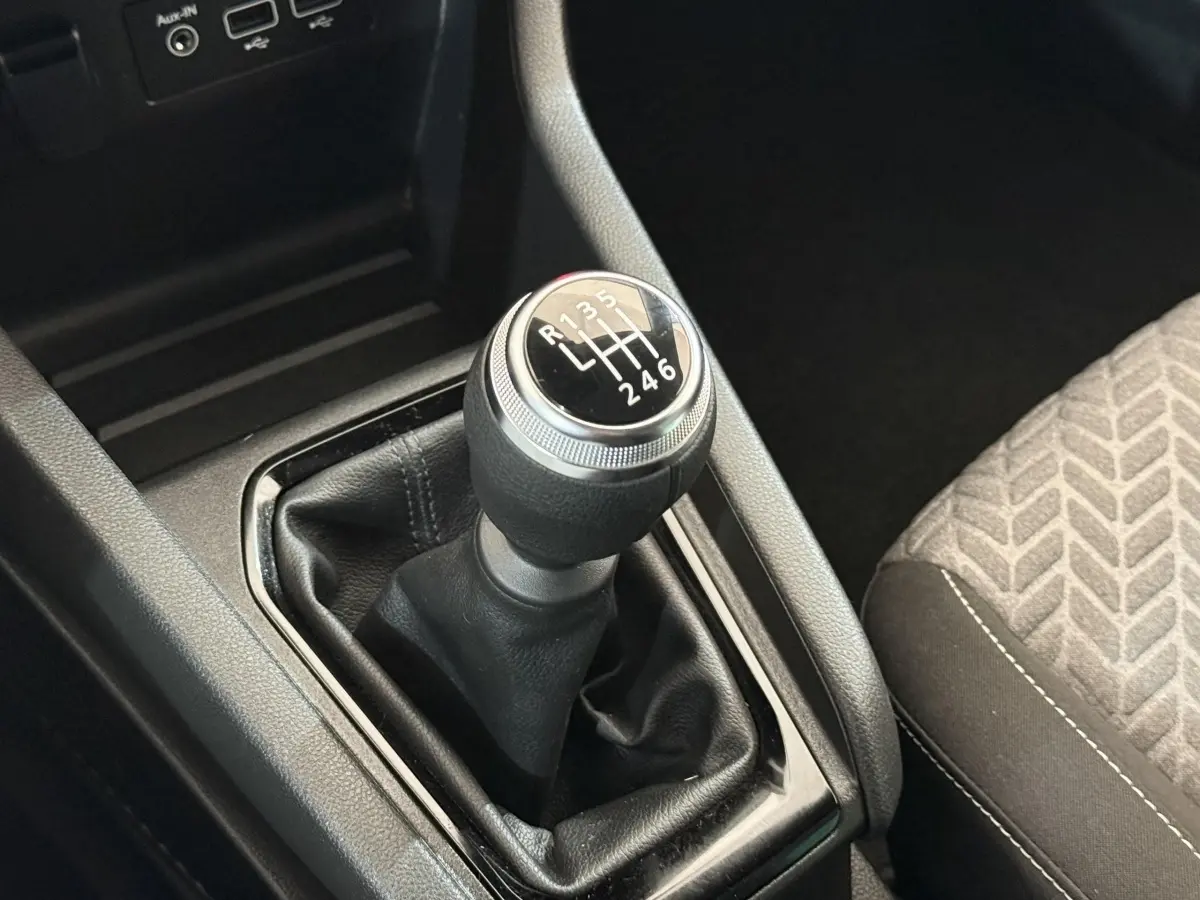Le levier de vitesses manuel noir de la Renault Clio Evolution TCe 100 GPL, avec console et siège tissu gris à motifs.