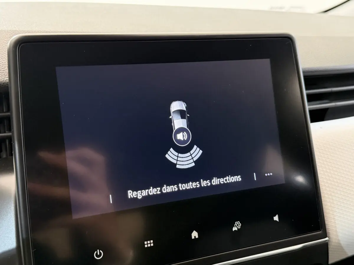 Écran tactile central affichant l'alerte de détection d'obstacles dans une Renault Clio blanche, vue intérieure.