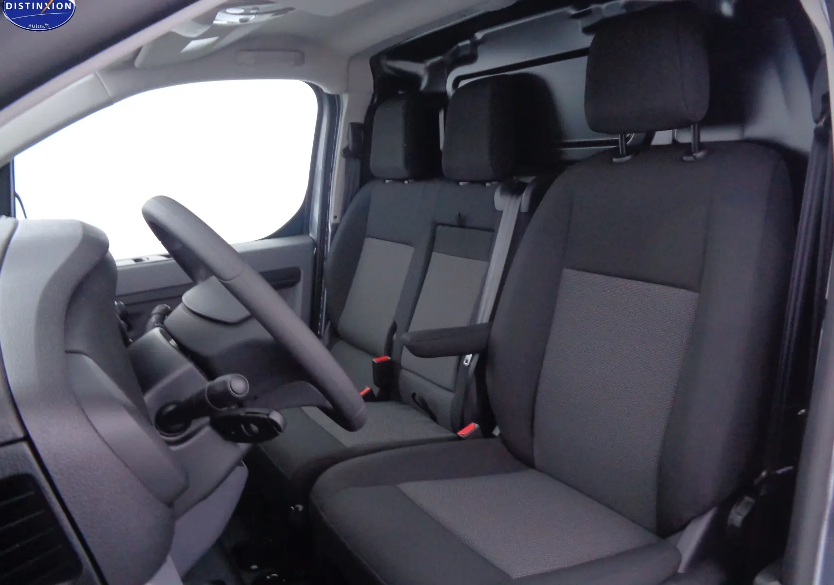 Vue intérieure côté conducteur du Peugeot Expert Fourgon 2022, sièges tissu noir et gris avec accoudoir central.