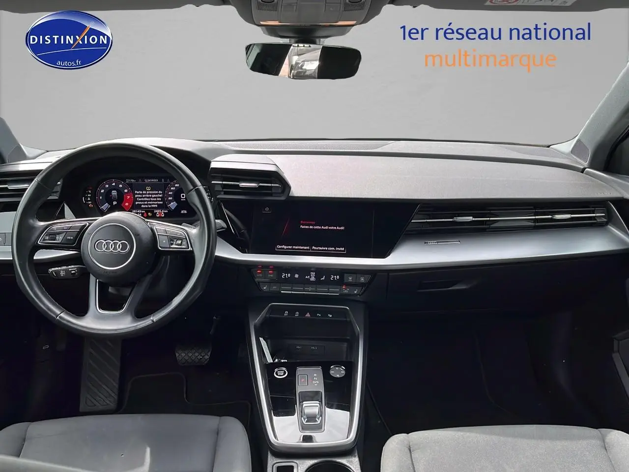 Intérieur de l'Audi A3 Sportback 2023 vu de face, tableau de bord moderne avec écran digital et volant cuir multifonction.