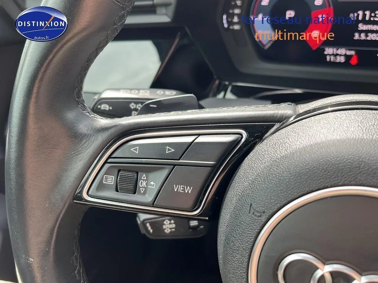 Gros plan sur les commandes gauche du volant cuir multifonction d'une Audi A3 Sportback gris Manhattan 2023.