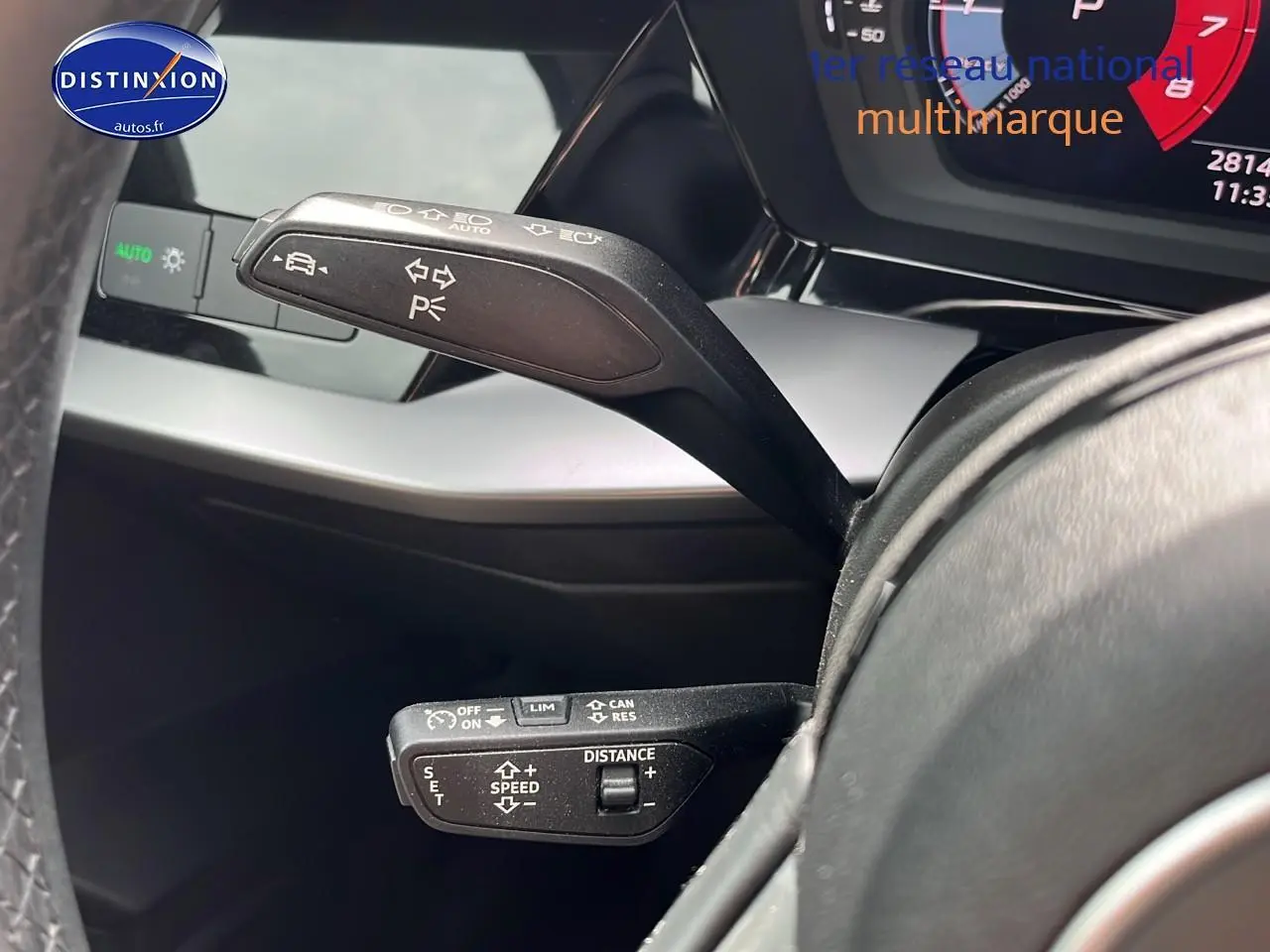 Gros plan sur les commandes au volant d'une Audi A3 Sportback 2023 gris Manhattan, affichage digital partiel visible.