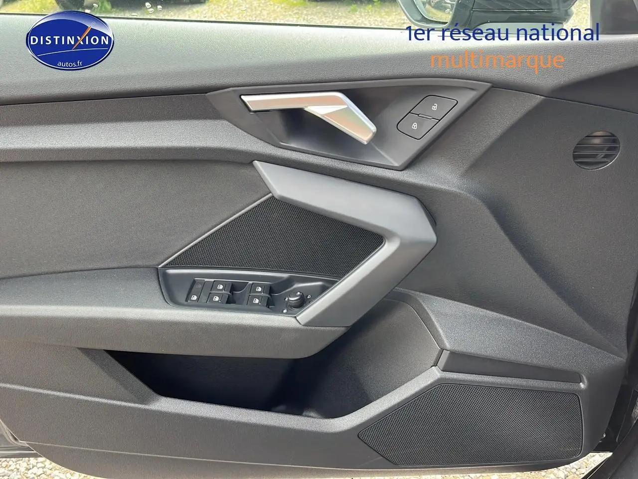 Détail de la porte avant gauche de l'Audi A3 Sportback 2023 avec commandes de vitres et poignée argentée.