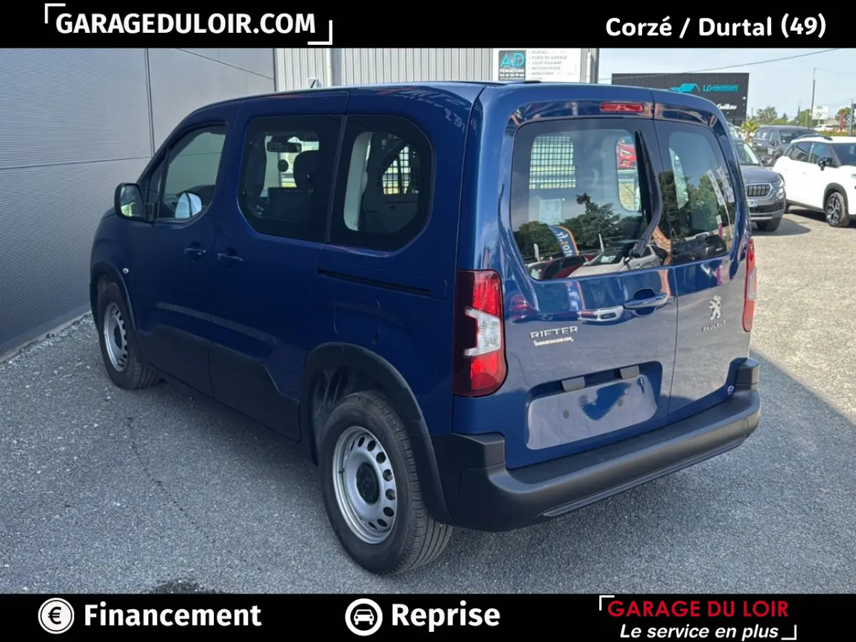 Vue 3/4 arrière gauche d'un Peugeot Rifter bleu 2024 avec portes arrière vitrées et jantes acier simples.