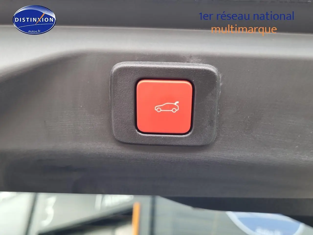 Bouton rouge d'ouverture électrique du coffre visible sur le hayon intérieur d'un Peugeot 3008 blanc.