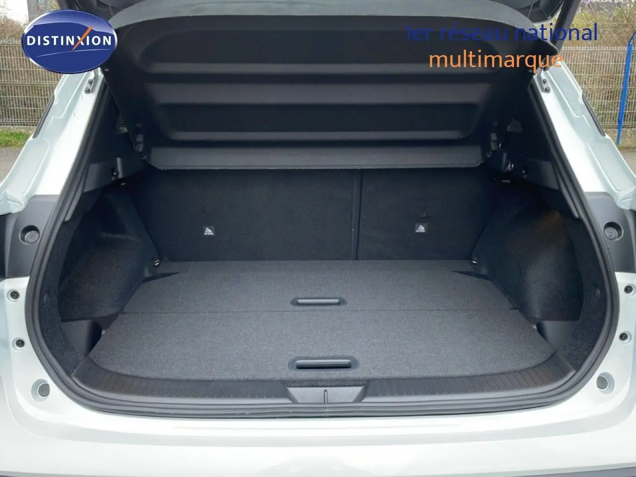 Coffre ouvert en vue arrière d’un Nissan Qashqai blanc nacré, montrant un espace de chargement plat et spacieux.