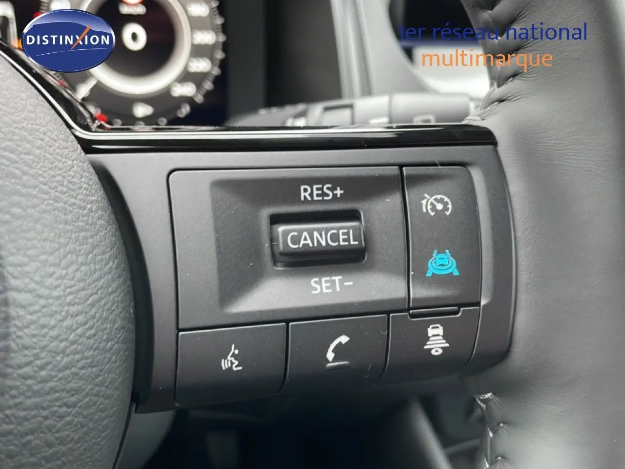 Gros plan sur les commandes au volant du Nissan Qashqai blanc nacré, mettant en valeur les boutons de régulateur de vitesse et assistance conduite.