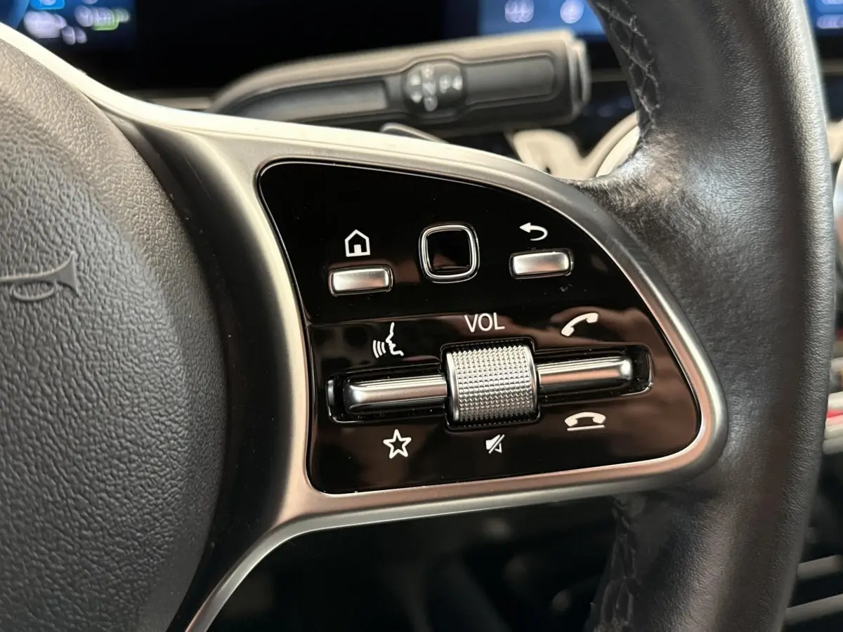 Gros plan sur les commandes du volant cuir noir d’une Mercedes GLA 250 e Business Line 2021, avec molette volume.