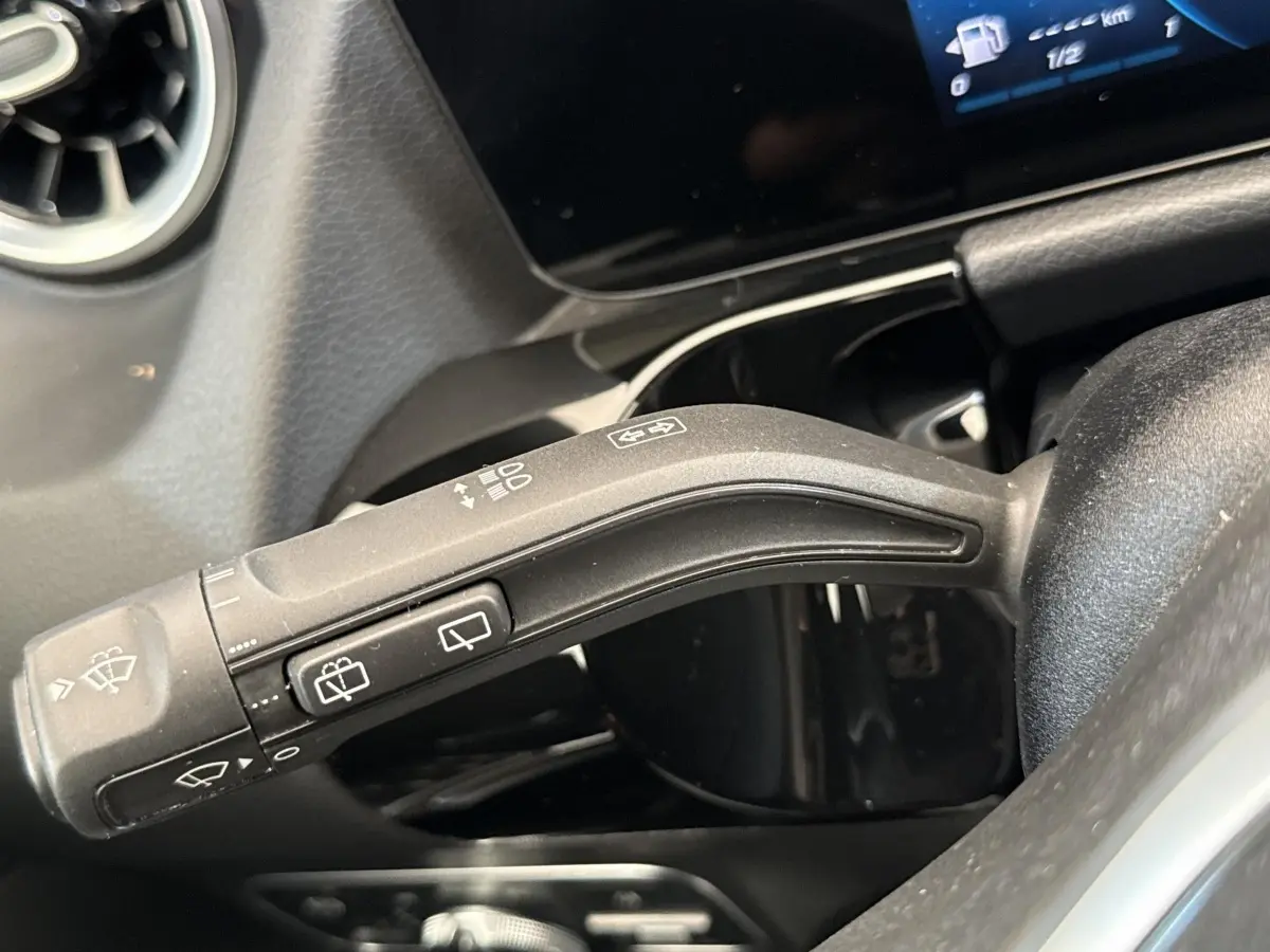 Gros plan sur la commande de essuie-glaces à gauche du volant dans l’habitacle noir du Mercedes GLA bleu 2021.
