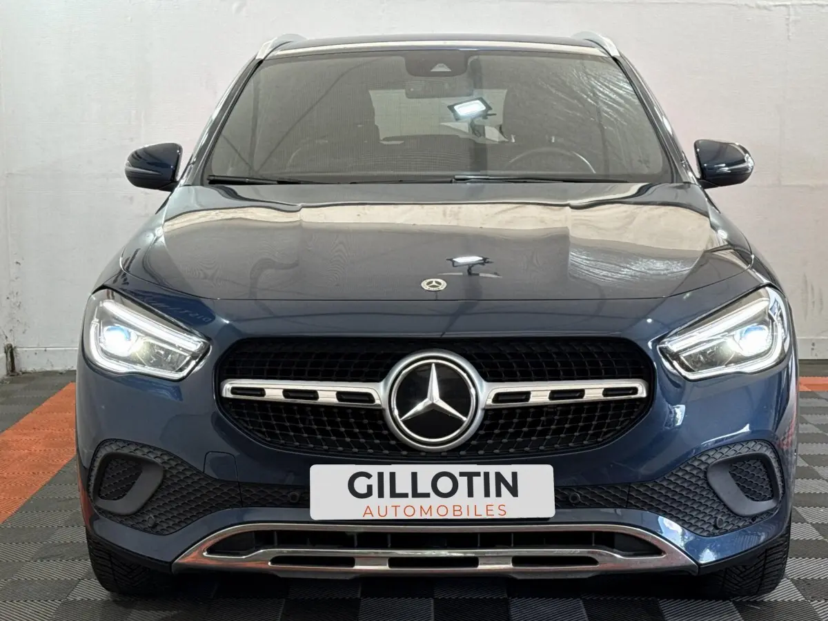 Vue frontale d’un Mercedes GLA 250 e Business Line bleu avec calandre chromée et phares LED allumés.