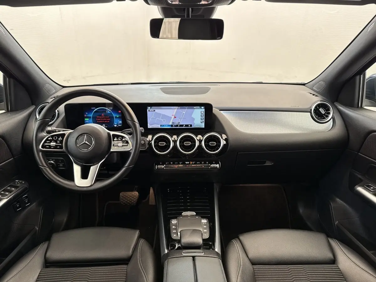 Vue intérieure avant du tableau de bord noir du Mercedes GLA 250 e Business Line avec écran tactile et volant cuir multifonctions.