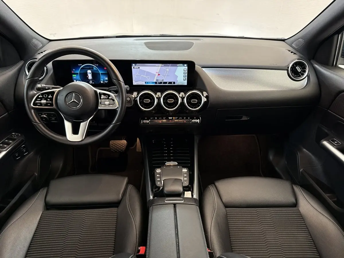 Vue intérieure avant du tableau de bord et volant cuir noir du Mercedes GLA 250 e Business Line 2021 avec écran tactile et navigation.
