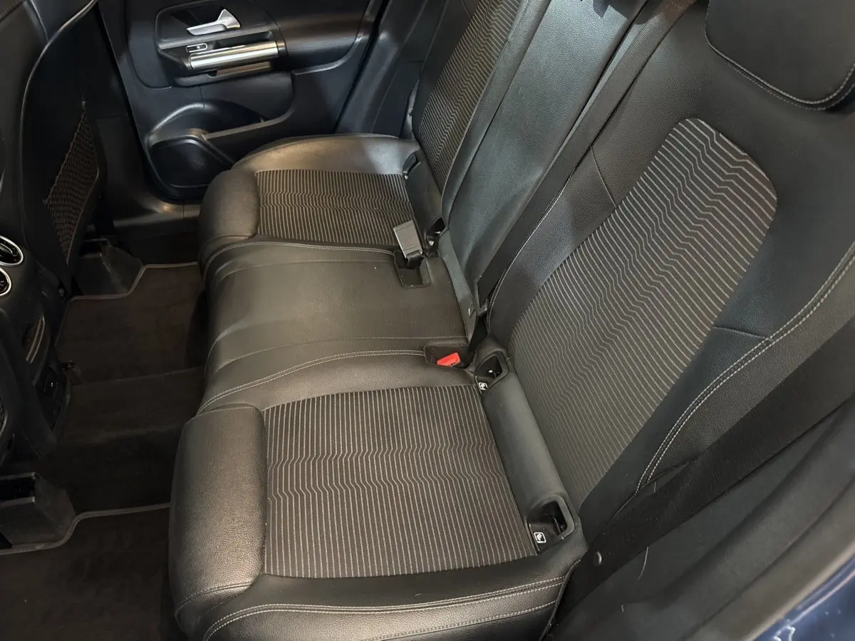 Vue intérieure côté gauche montrant la banquette arrière noire avec inserts tissu et ceinture de sécurité d’une Mercedes GLA 250 e bleu.
