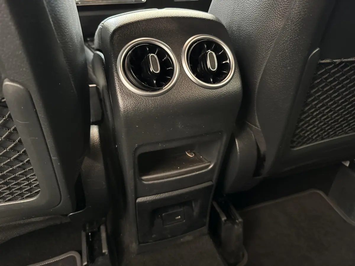 Vue rapprochée des aérateurs arrière et prise USB sur la console centrale noire du Mercedes GLA bleu 2021.