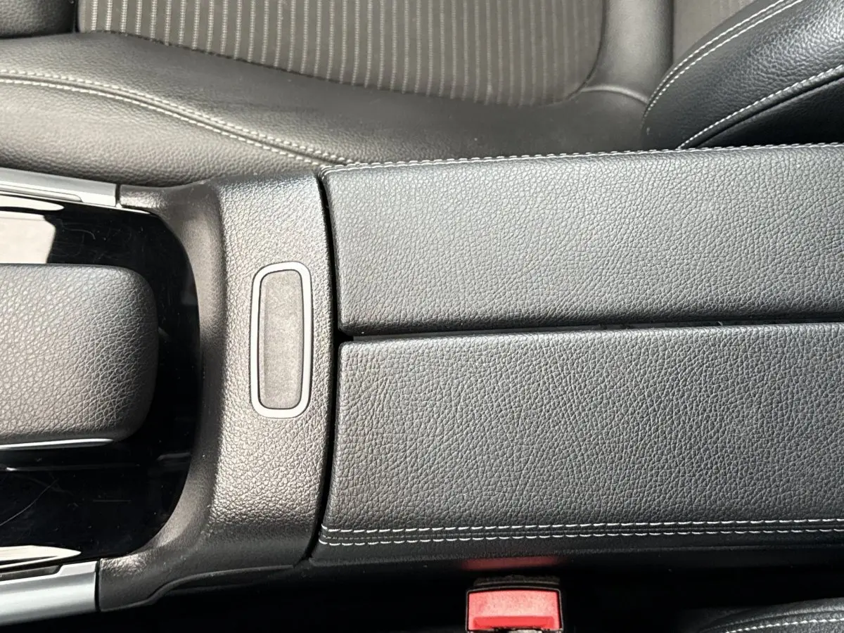Gros plan sur l'accoudoir central en cuir noir avec surpiqûres blanches de la Mercedes GLA 250 e Business Line 2021.