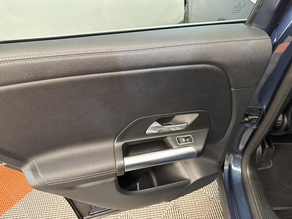 Intérieur de la porte côté gauche d’un Mercedes GLA 250 e Business Line bleu, avec poignée argentée et bouton de verrouillage.