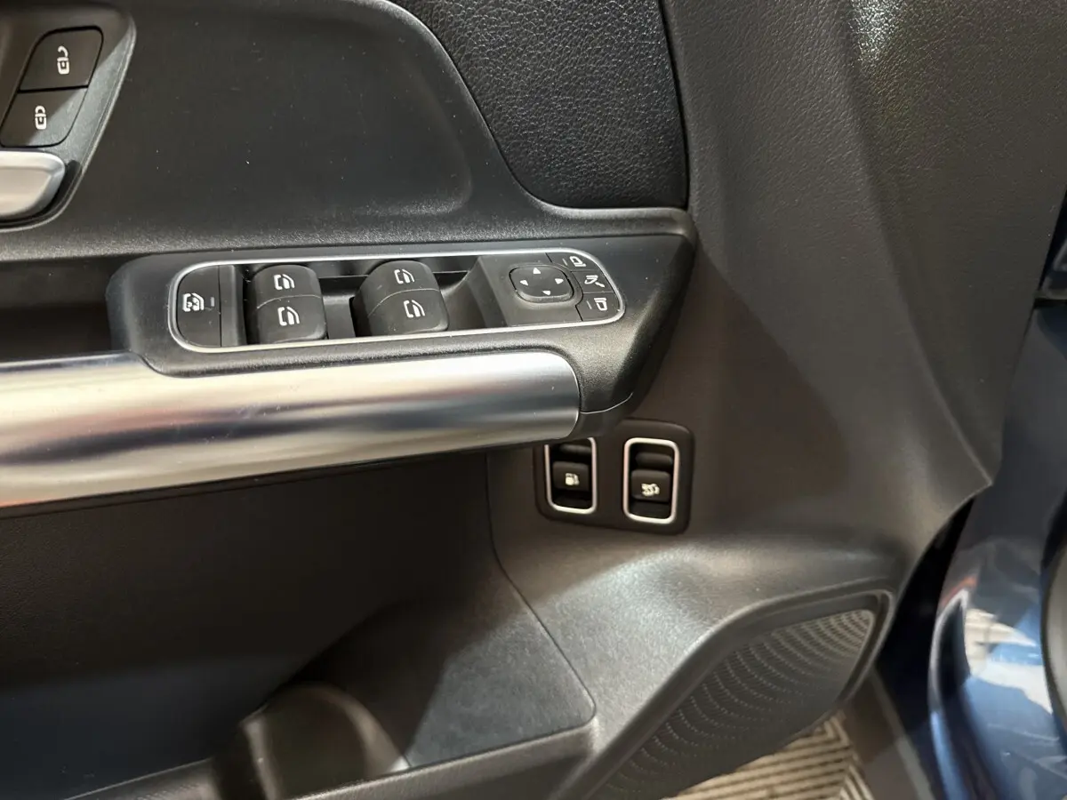 Gros plan sur la porte avant gauche du Mercedes GLA bleu, avec commandes de vitres et rétroviseurs électriques.