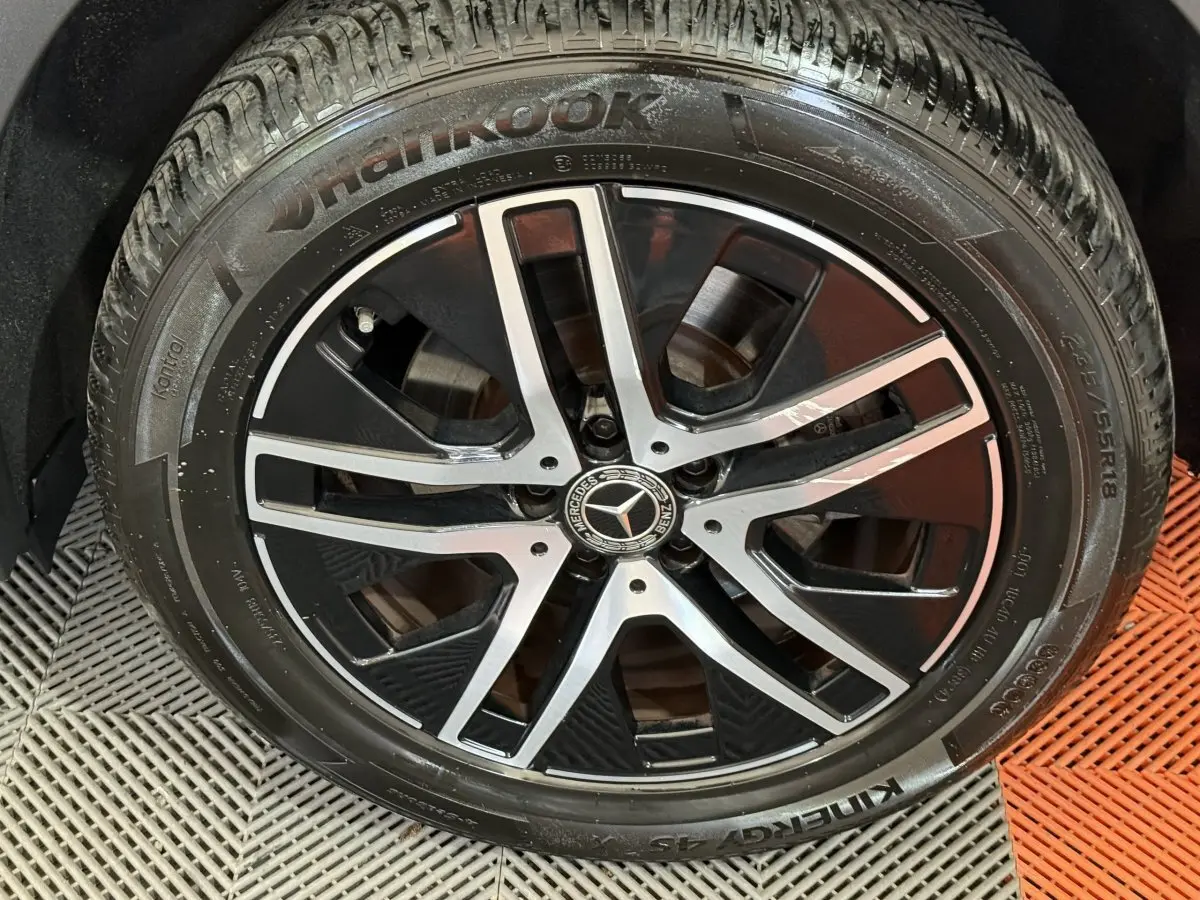 Gros plan sur la jante alliage noire et argentée avec logo Mercedes, montée sur pneu Hankook du Mercedes GLA bleu.