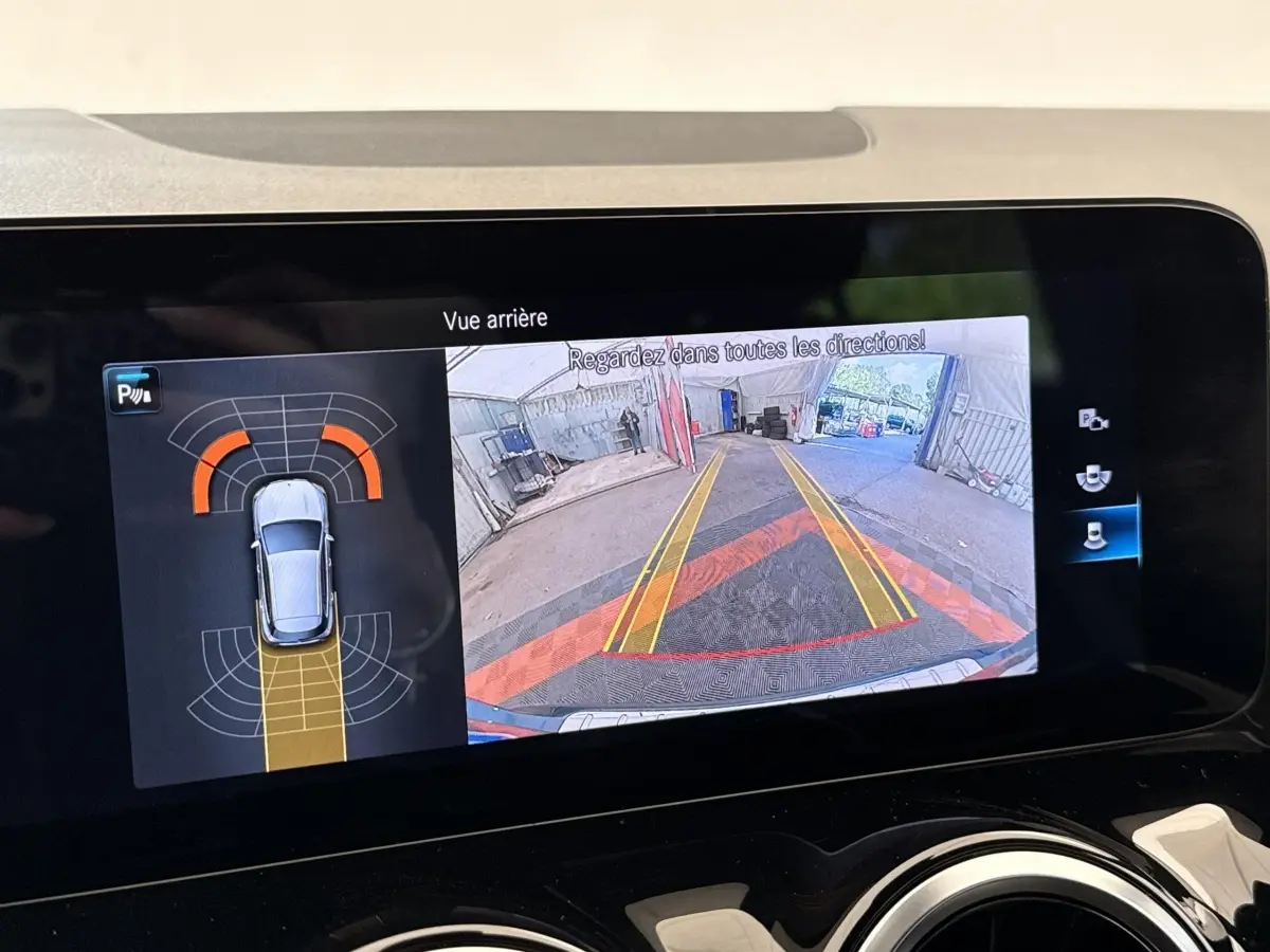 Écran tactile intérieur montrant la caméra de recul et l’aide au stationnement du Mercedes GLA bleu 3/4 arrière.