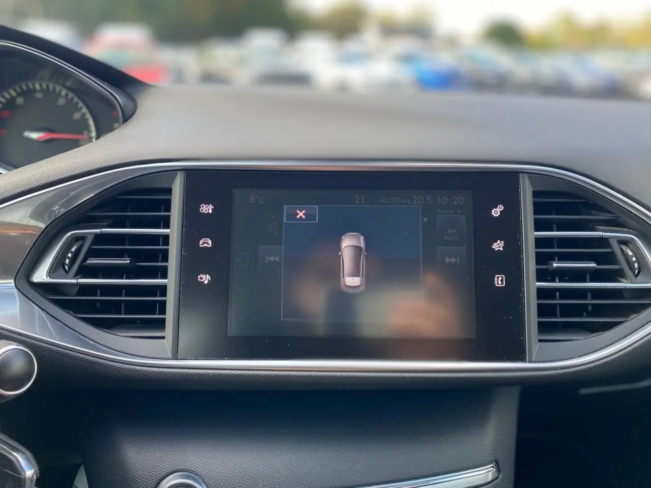 Écran tactile central du tableau de bord de la Peugeot 308 gris aluminium avec affichage de l'aide au stationnement.