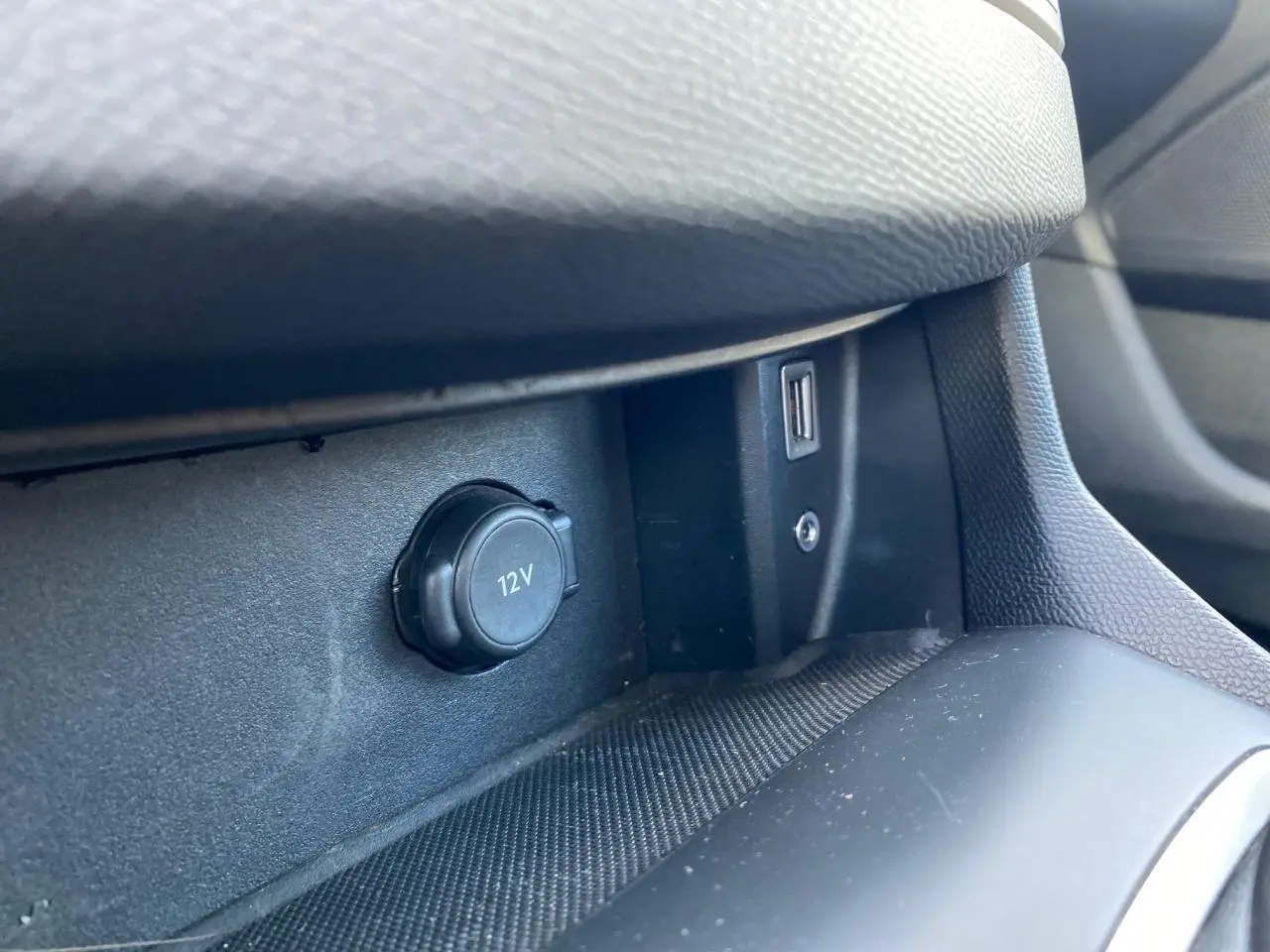 Prise 12V et port USB en gros plan sur la console centrale intérieure de la Peugeot 308 gris aluminium.