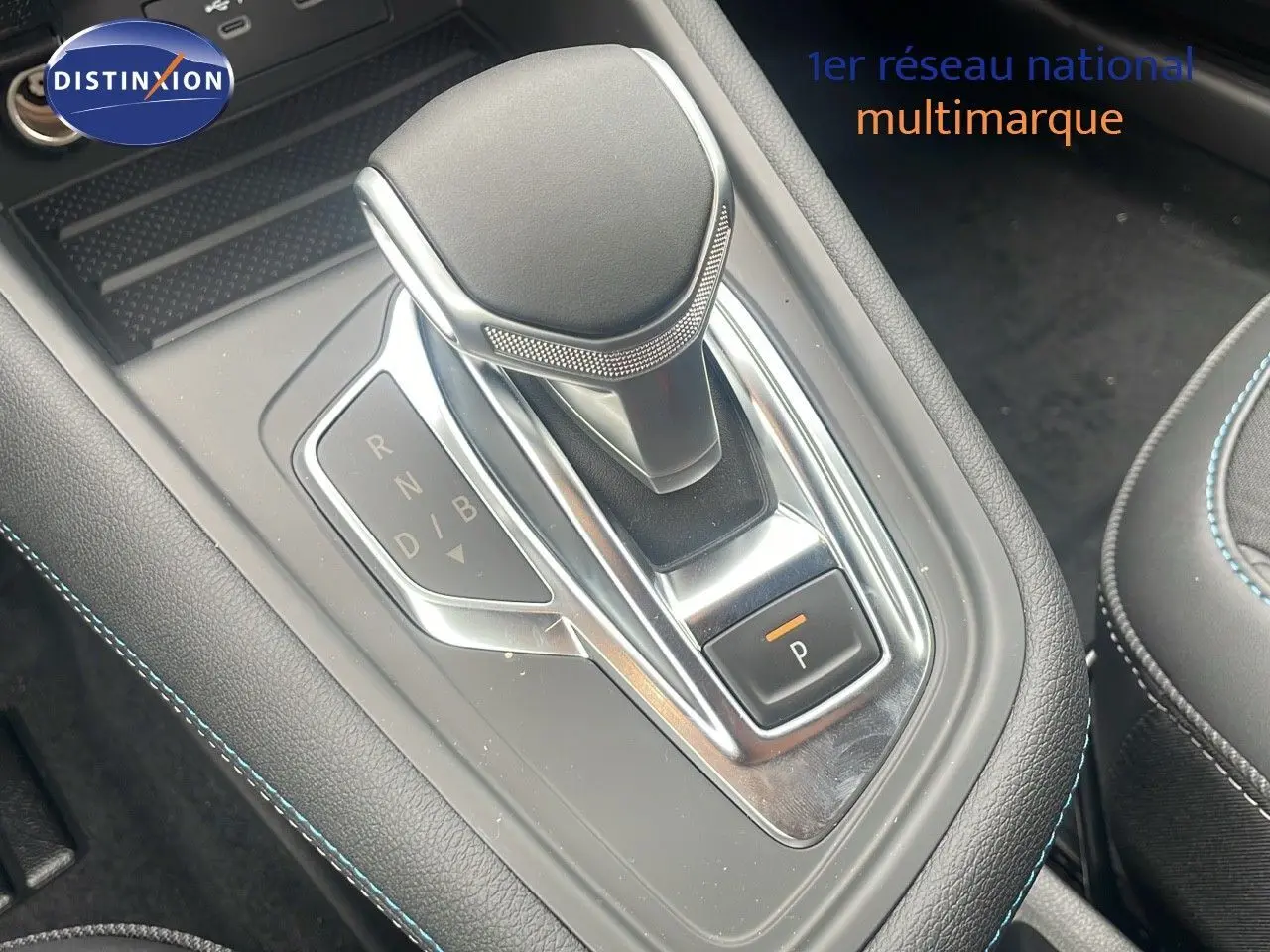 Le levier de vitesses automatique du Renault Captur E-Tech hybride 2025, avec coutures bleues sur console noire.