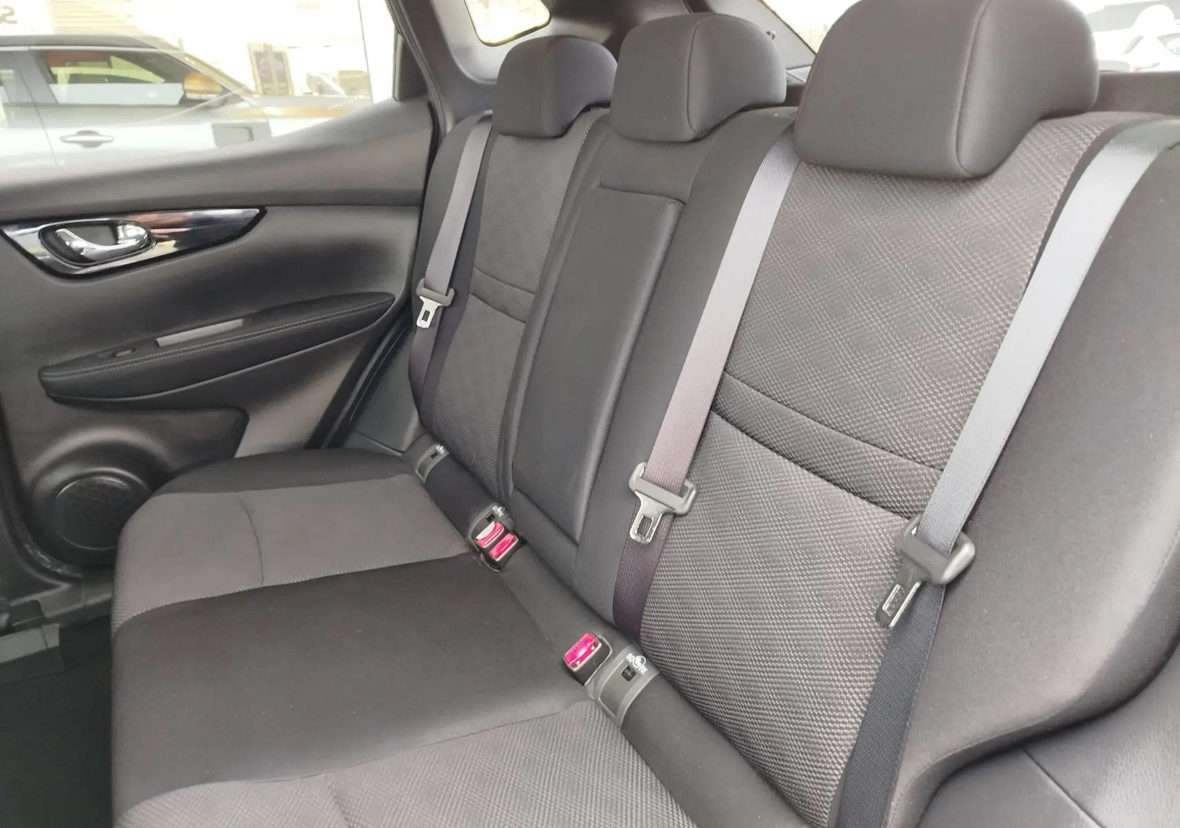 Gros plan sur la poignée intérieure chromée et les commandes des vitres côté conducteur du Nissan Qashqai bronze Ultime 2017.