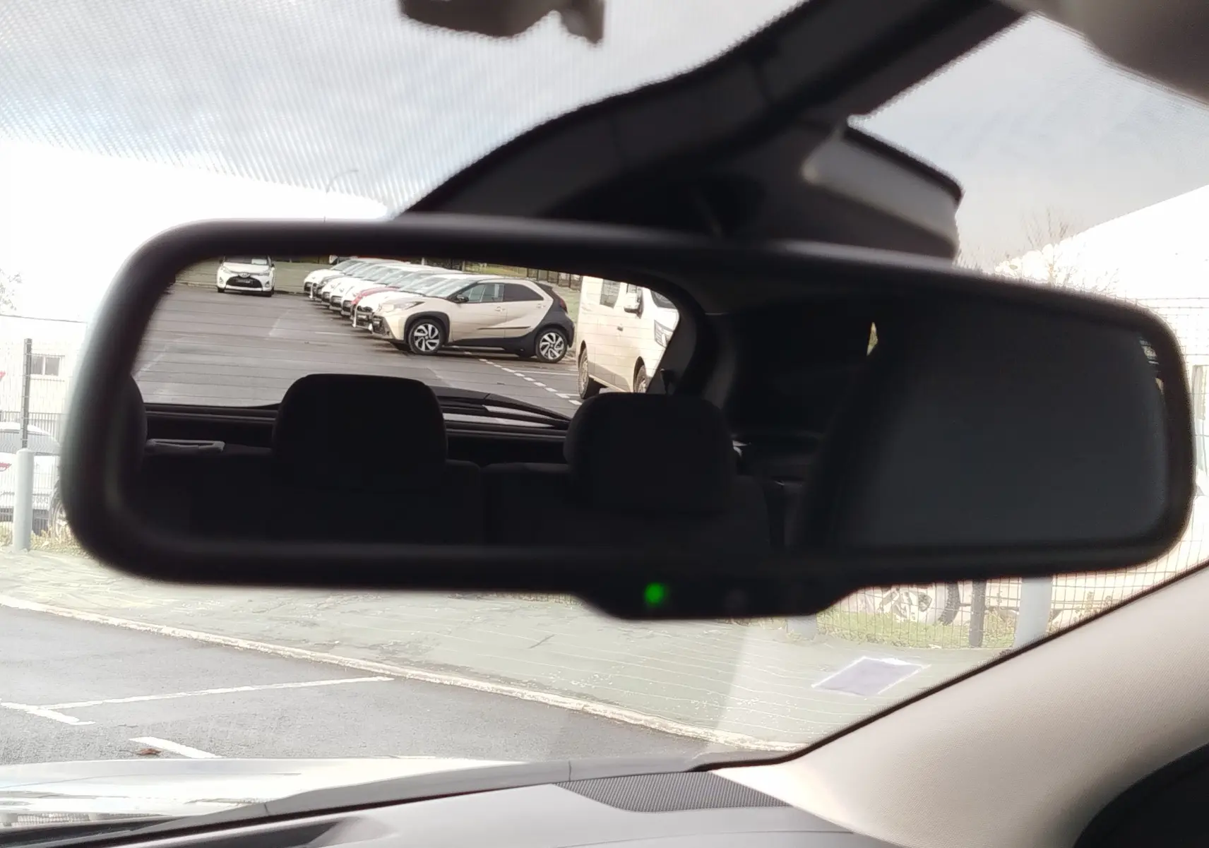 Vue 3/4 arrière droite d'un Nissan Qashqai bronze Ultime avec jantes alliage et vitres teintées, stationné devant un showroom.