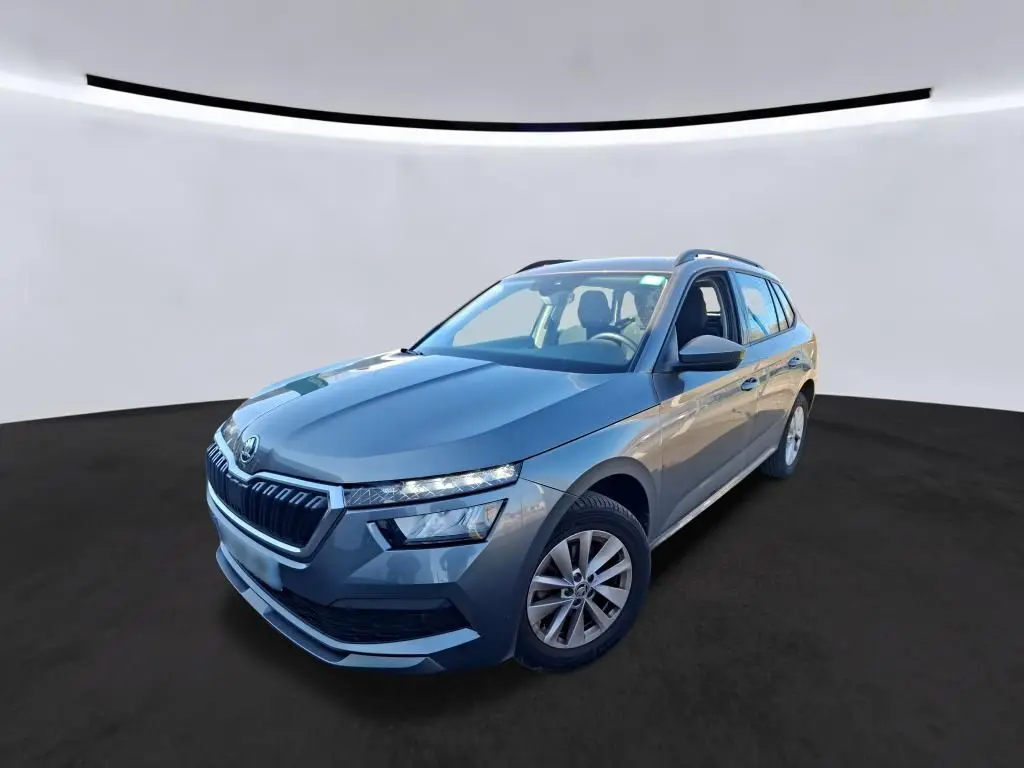 Vue 3/4 avant droite d'un Skoda Kamiq gris foncé 2023 avec calandre distinctive et toit ouvrant visible.