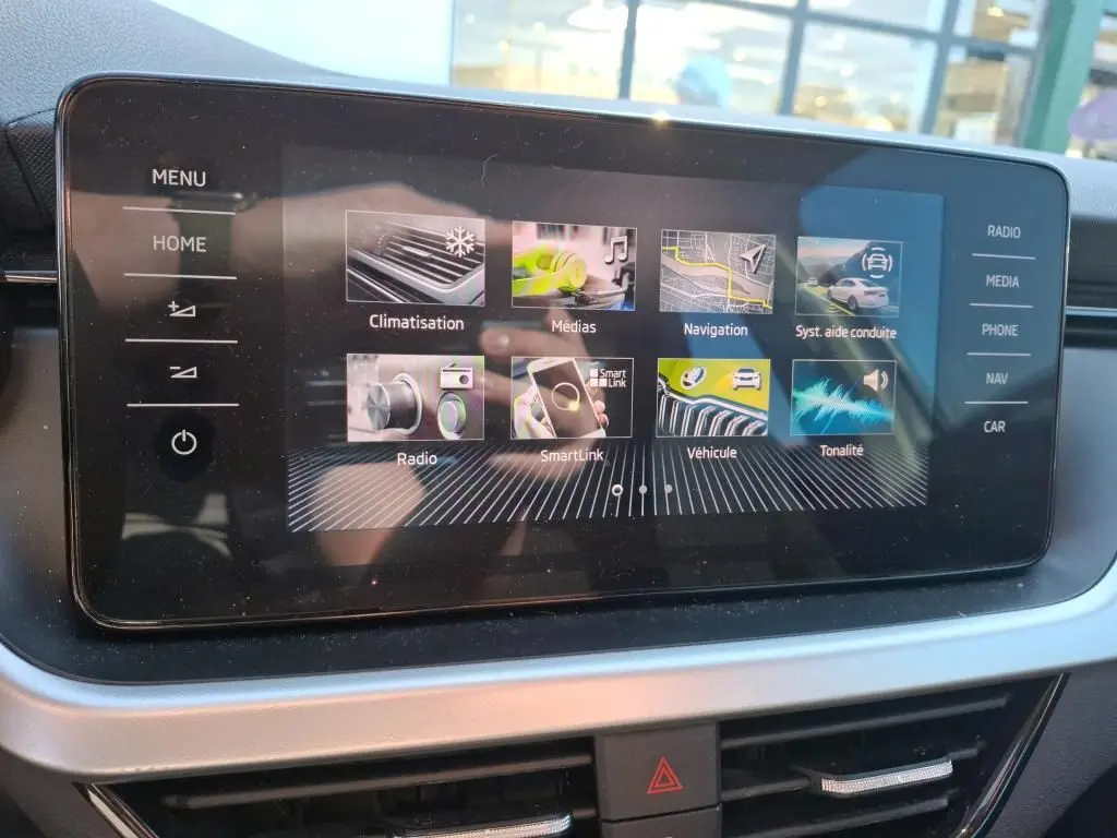 Écran tactile central du Skoda Kamiq 2023 affichant les menus de climatisation, navigation et médias, intérieur noir.