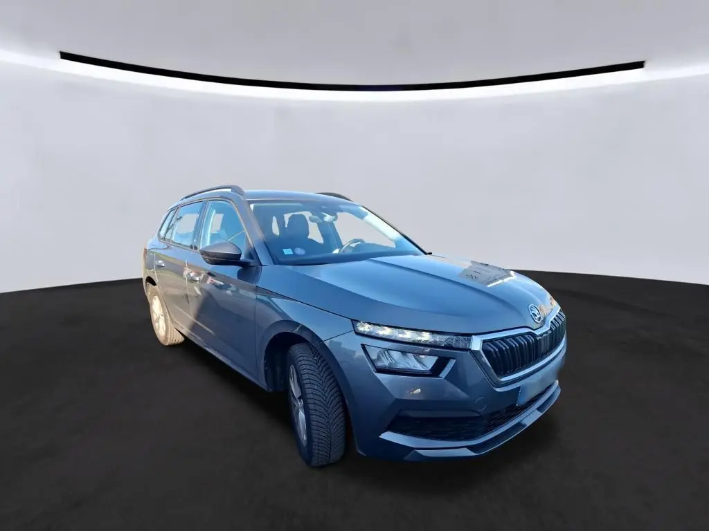 Vue 3/4 avant droit d'une Skoda Kamiq gris foncé 2023 avec calandre distinctive et phares LED fins.