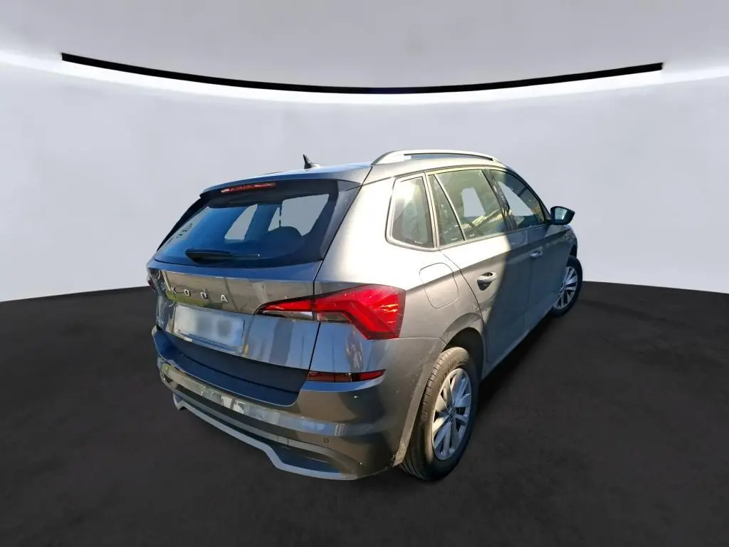 Vue 3/4 arrière droite d'un Skoda Kamiq gris foncé 2023 avec toit ouvrant et feux arrière LED distinctifs.
