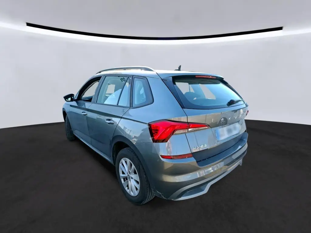 Vue 3/4 arrière droite d'un Skoda Kamiq gris foncé 2023, compact avec feux arrière LED et toit avec barres de toit.