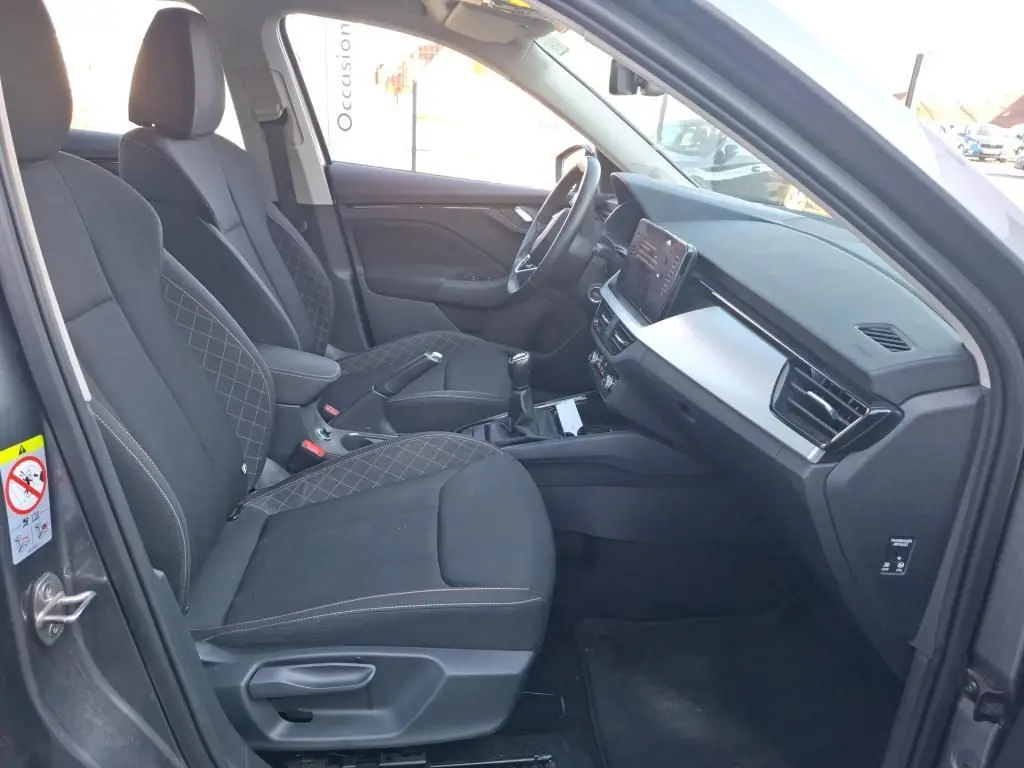 Intérieur avant droit du Skoda Kamiq gris foncé 2023, sièges tissu noir avec surpiqûres et tableau de bord moderne.
