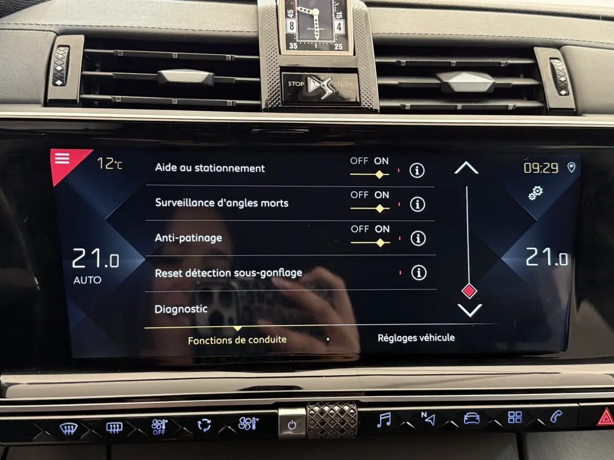 Écran tactile central du DS7 Crossback gris foncé montrant les réglages d’aide à la conduite et la climatisation à 21°C.