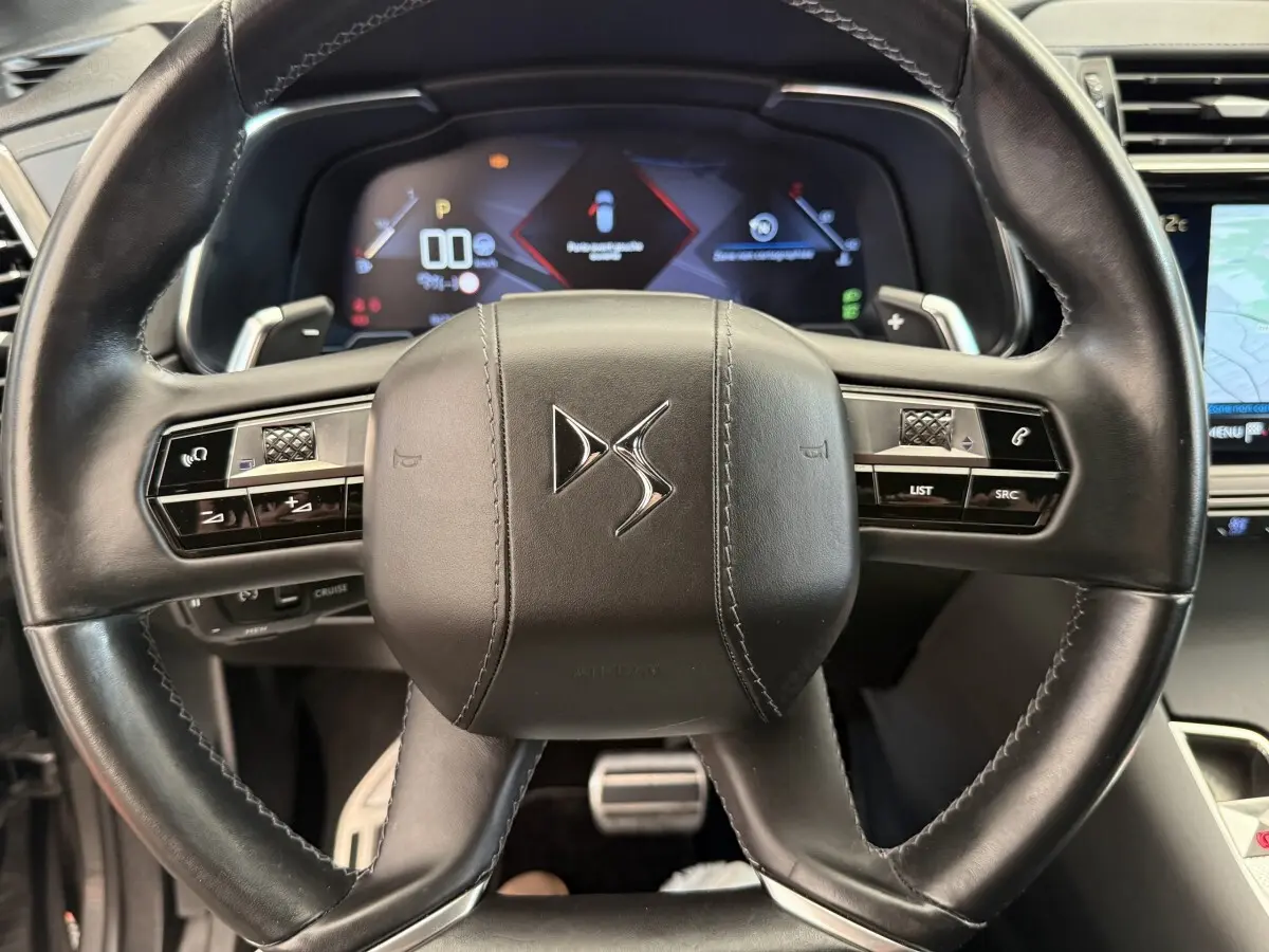 Vue rapprochée du volant cuir noir de la DS7 Crossback avec tableau de bord numérique et commandes intégrées.