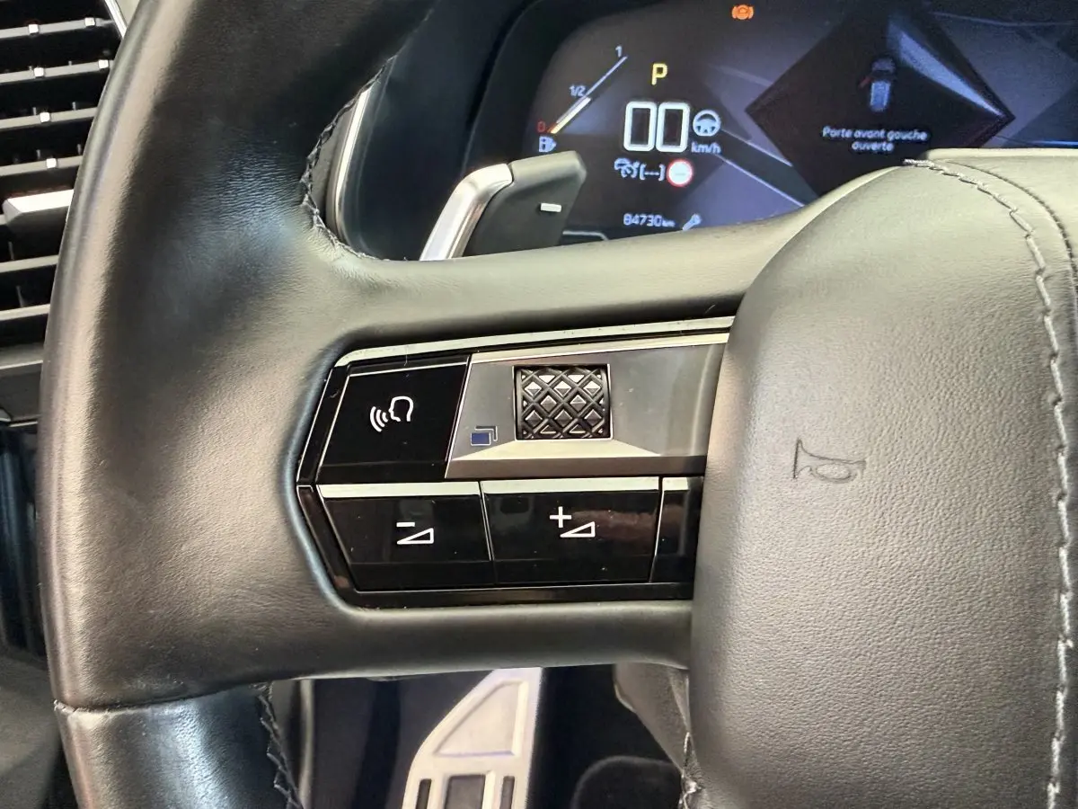 Gros plan sur le volant cuir noir côté gauche du DS7 Crossback avec commandes vocales et tableau de bord numérique.