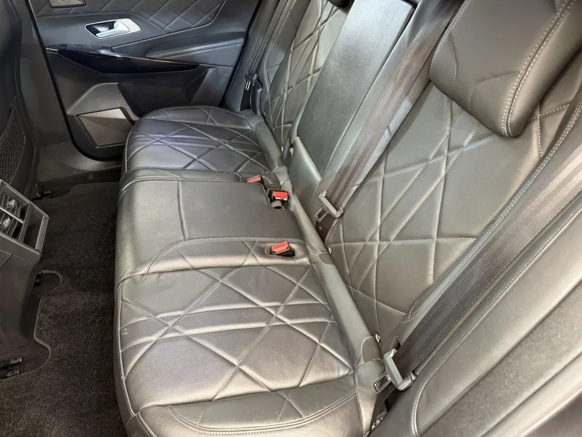 Vue rapprochée de la banquette arrière en cuir noir matelassé du DS7 Crossback gris foncé, avec ceintures et porte-gobelets.