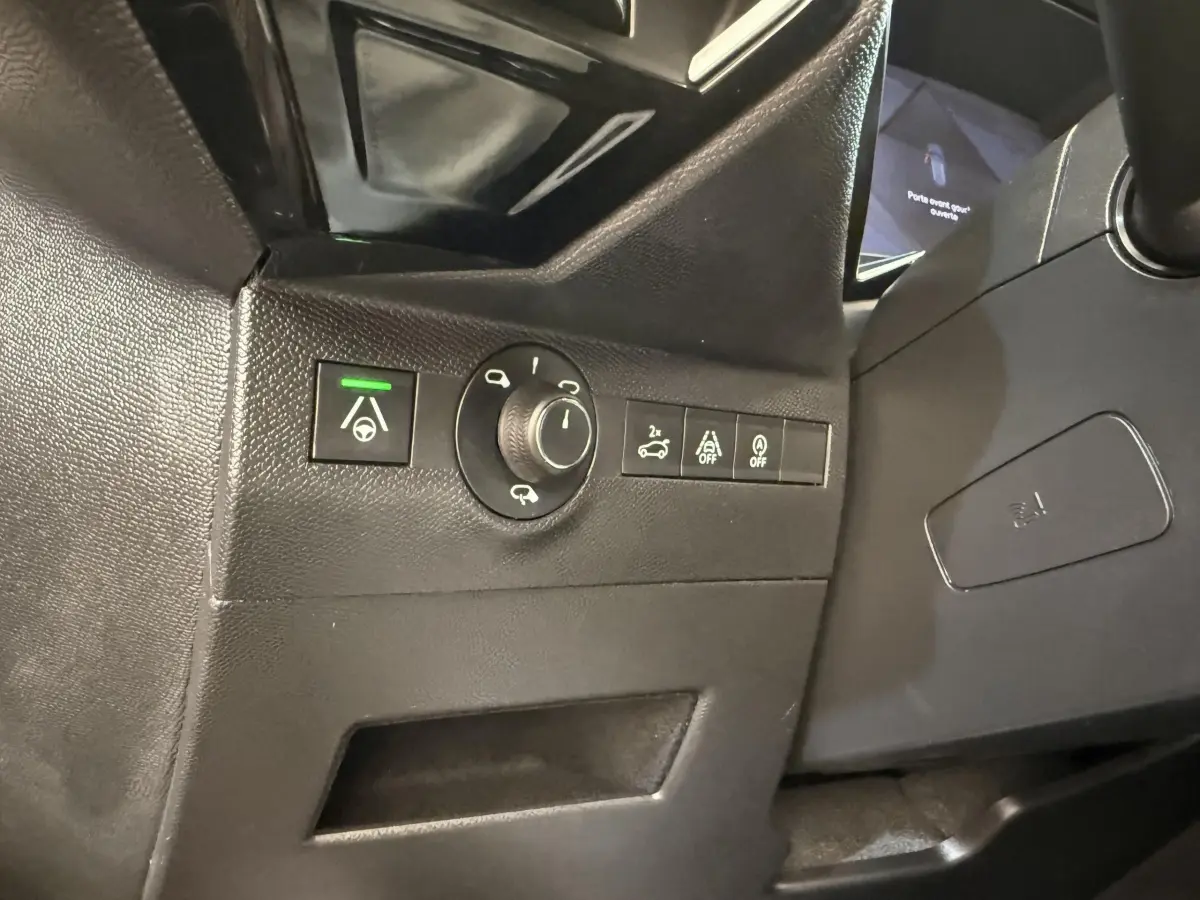 Gros plan sur les commandes noires du tableau de bord côté gauche du DS7 Crossback gris foncé, avec bouton d'aide à la conduite activé.
