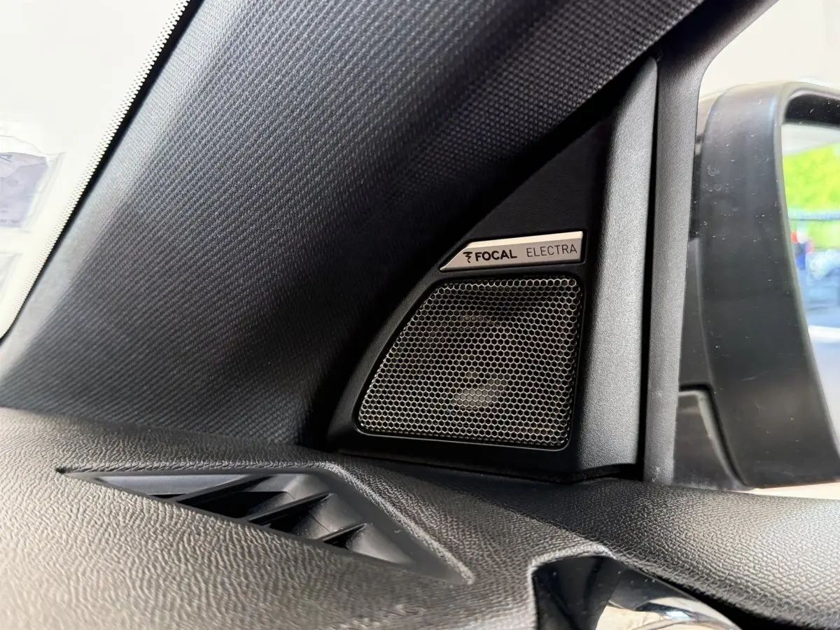 Gros plan sur haut-parleur Focal Electra côté gauche dans l’habitacle du DS7 Crossback gris foncé, avec rétro extérieur visible.