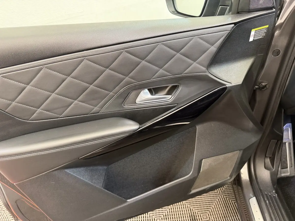 Gros plan sur la porte intérieure côté conducteur du DS7 Crossback gris foncé avec surpiqûres losanges et insert noir brillant.