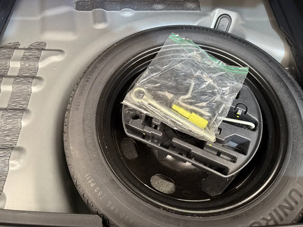 Gros plan sur la roue de secours et le kit d’outils dans le coffre d’un DS7 Crossback gris foncé.
