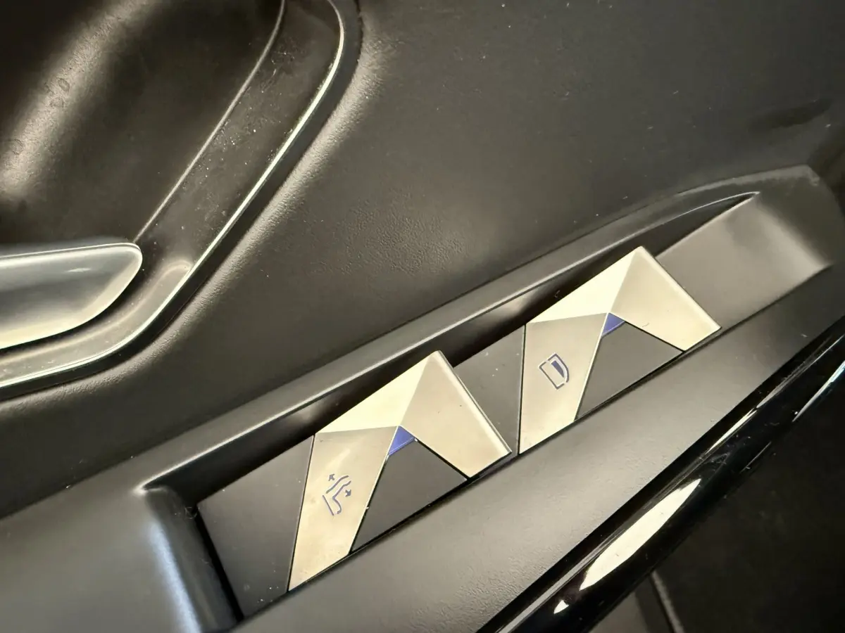 Gros plan sur les commandes de réglage des sièges en métal brossé dans une DS7 Crossback gris foncé.
