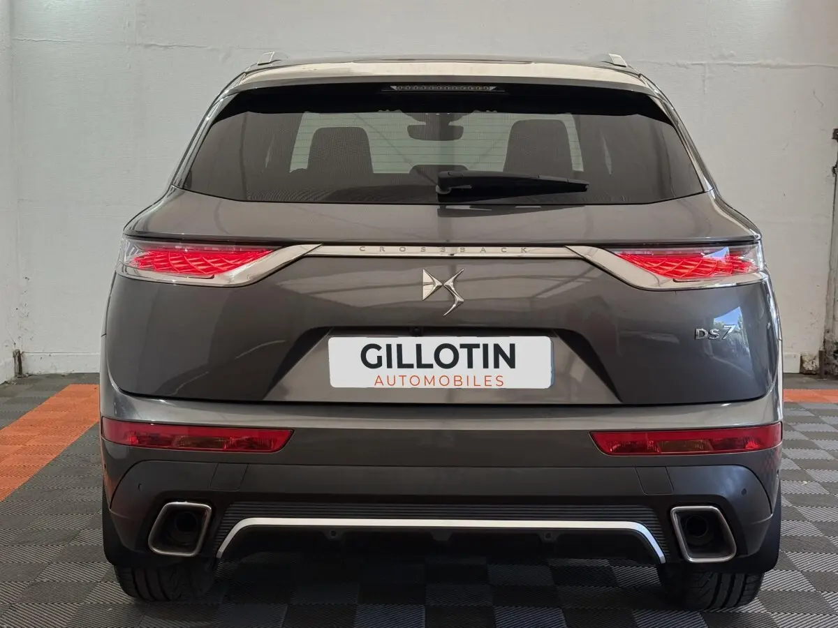 Vue arrière d'un DS7 Crossback gris foncé avec feux arrière LED distinctifs et double sortie d'échappement.