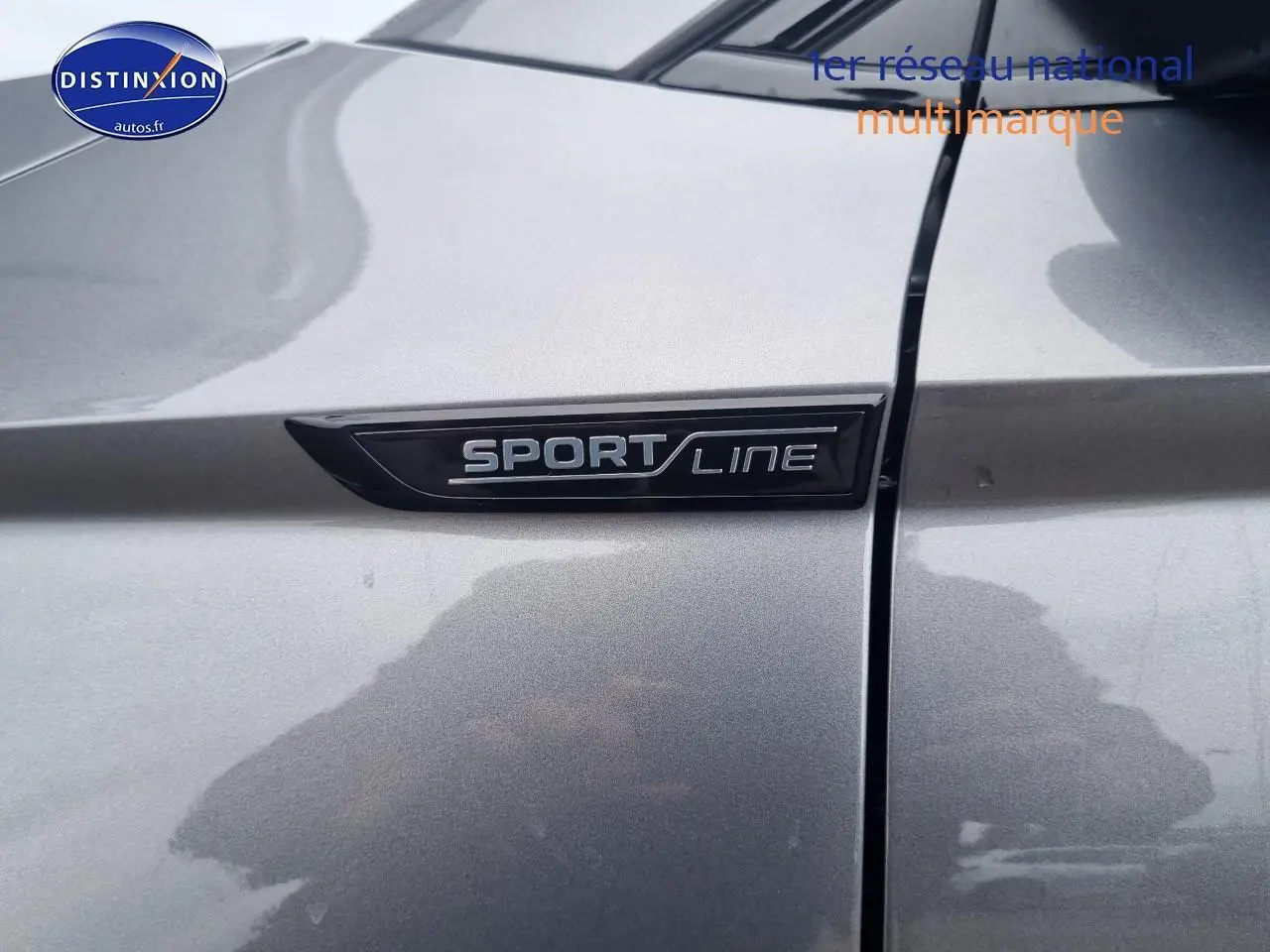 Gros plan sur l'emblème Sportline sur la portière gris graphite du Skoda Karoq 2025 côté avant droit.